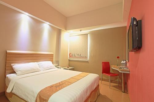 a hotel room with a bed and a red chair at Metland Hotel Bekasi in Bekasi