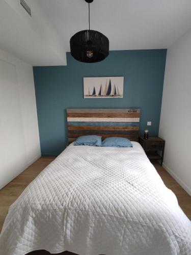 une chambre avec un grand lit avec un mur bleu dans l'établissement cottage chaleureux proche de l'océan, à Grayan-et-lʼHôpital