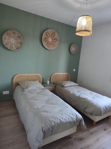 deux lits dans une chambre aux murs verts dans l'établissement cottage chaleureux proche de l'océan, à Grayan-et-lʼHôpital