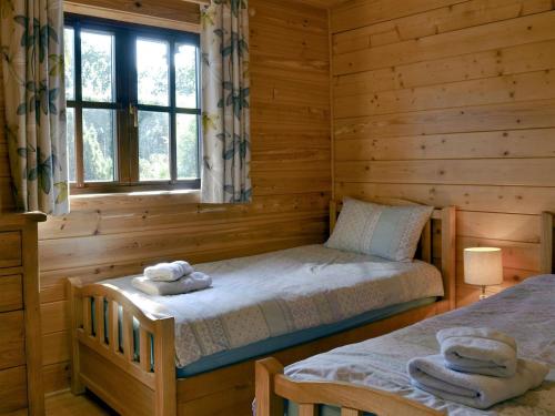 een slaapkamer met 2 bedden in een blokhut bij Otter - Uk12540 in Witheridge