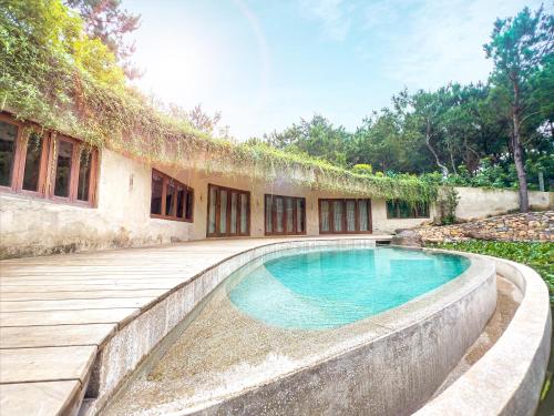 an outdoor swimming pool with a patio and a house at Amaya Retreat in Sóc Sơn