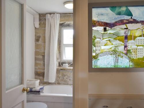 baño con bañera y una pintura en la pared en Club House, en Hebden Bridge