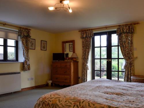 a bedroom with a bed and a dresser and windows at The Old School Penallt in Mitchel Troy