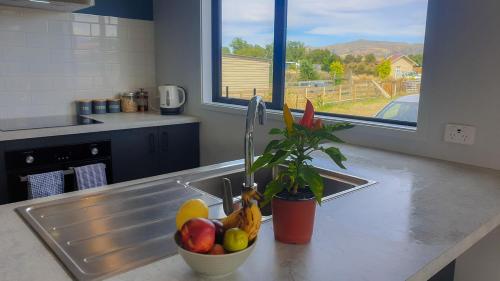 a kitchen counter with a sink with a bowl of fruit at Rough Ridge Cottage ~ your haven in Central Otago in Oturehua