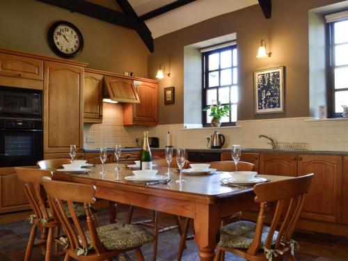 uma cozinha com uma mesa de madeira com cadeiras e um relógio em The Old School Penallt em Mitchel Troy