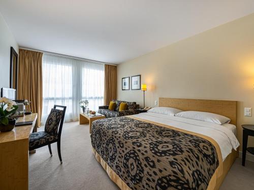 ein Hotelzimmer mit einem großen Bett und einem Wohnzimmer in der Unterkunft Jade Manotel in Genf