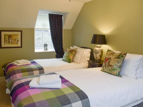 two beds in a room with a window at Smiddy Cottage in Aberfeldy