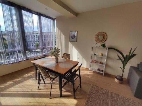 een eettafel en stoelen in een kamer met grote ramen bij By The Cathedral, 1 bed flat in Varna