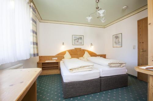 a bedroom with two beds and a desk at Hotel & Appartements Alpenresidenz Viktoria in Neustift im Stubaital