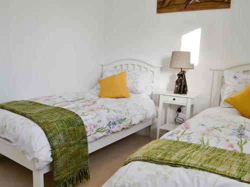 a bedroom with two beds and a table with a lamp at 3 Old Posting Stables in Gatehouse of Fleet
