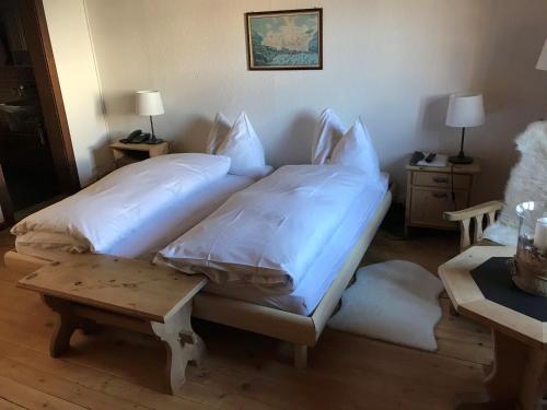 a bedroom with two beds with white sheets at Hotel Klarer in Zuoz