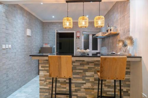 a kitchen with a bar with two chairs and lights at Treasure Villa in Anse Possession