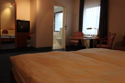 a hotel room with a bed and a desk and a television at Hotel-Gasthof Die Post Brennerei Frankenhöhe in Schillingsfürst