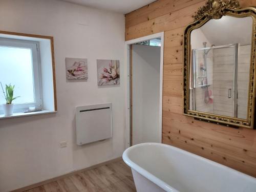 a bathroom with a white tub and a mirror at Chez Laetitia in Gérardmer