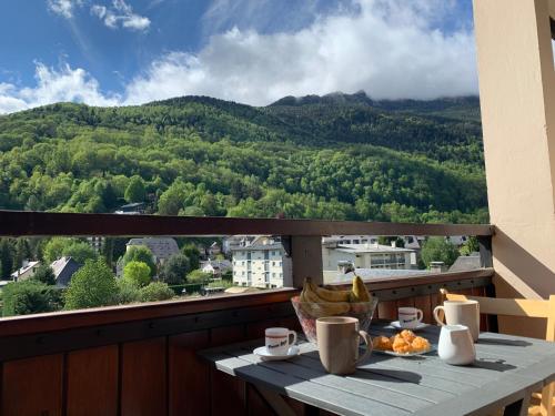 a table on a balcony with a view of a mountain at Les Cimes 58 m2 - PISCINE INTÉRIEURE Vue Montagne Centre Village - Parking Privé - Ménage de fin de séjour compris in Saint-Lary-Soulan