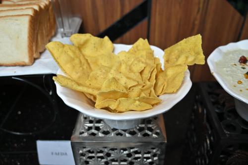 a plate of chips on a counter with a plate of bread at Hotel Tip Top International Pune in Pune
