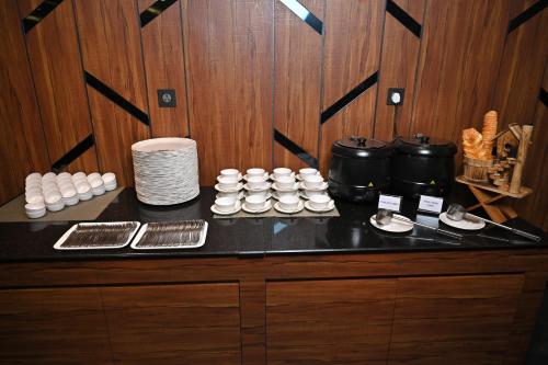 a counter with cups and plates on a table at Hotel Tip Top International Pune in Pune