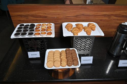 a counter with three trays of pastries and other pastries at Hotel Tip Top International Pune in Pune