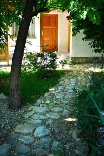 un camino de piedra con un árbol y una puerta en Casa de oaspeti adorabila aproape de natura, en Sărata-Monteoru