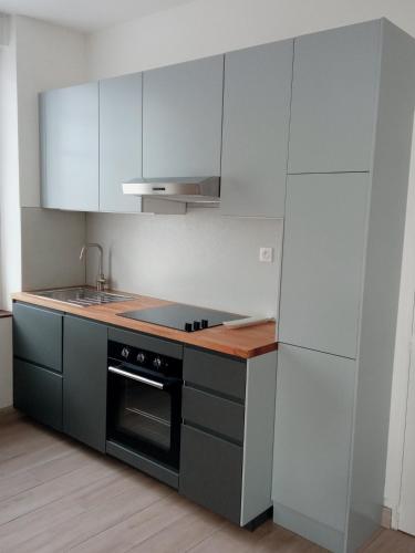 una cocina con armarios blancos y horno negro en Joli appartement moderne / proche de Dinard en Pleurtuit