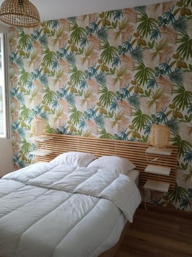 PleurtuitにあるJoli appartement moderne / proche de Dinardのトロピカルな壁紙のベッドルーム1室(大型ベッド1台付)