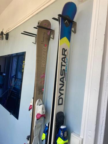 two skis and snowboards are hanging on a wall at Le « studio sur la Neste » dans le centre d’Arreau in Arreau