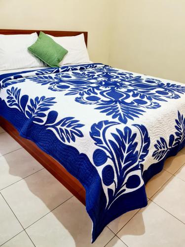 a bed with a blue and white blanket on it at Guest house KupuKupu39 in Kuta