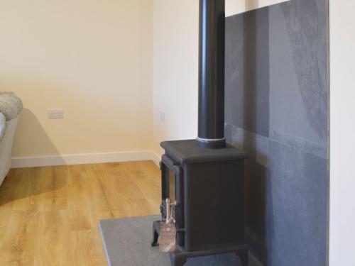 a black stove in a room with a wooden floor at Claymore Cottage in Whaligoe