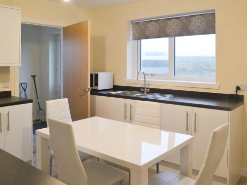 a kitchen with a white table and chairs and a window at Claymore Cottage in Whaligoe