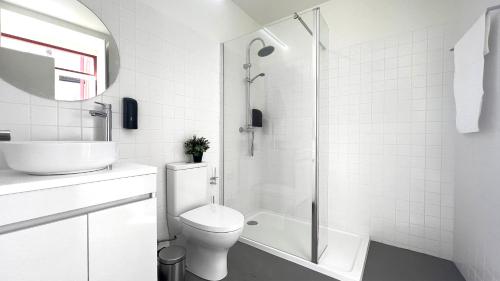 La salle de bains blanche est pourvue d'une douche et de toilettes. dans l'établissement Casa do Correio @ Casas do Pátio (1), à Coimbra