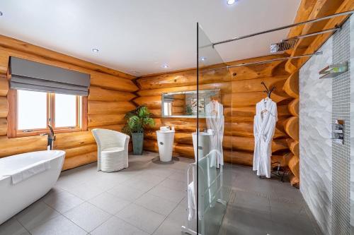 uma casa de banho com paredes de madeira, uma banheira e um lavatório. em The Log Cabins at The Vu em Bathgate