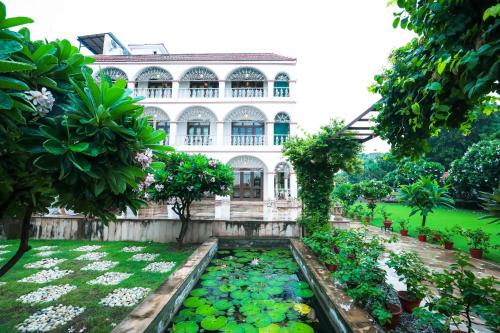 a garden in front of a building with a pond with lilies at Saptapuri by Royal Orchid Hotels Limited Varanasi in Varanasi