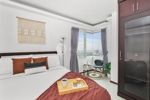 a bedroom with a bed with a tray of food on it at Gala by Kozystay - Thamrin in Jakarta