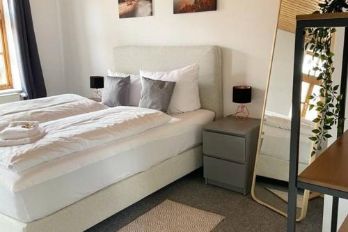 een slaapkamer met een wit bed, een tafel en een spiegel bij Ferienwohnung Till Eulenspiegel in Schöppenstedt