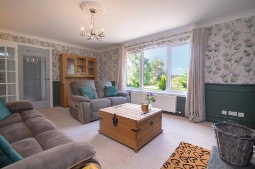 a living room with a couch and a table at Calm Scottish Country Escape with Hot Tub Sleeps 6 in Inverness
