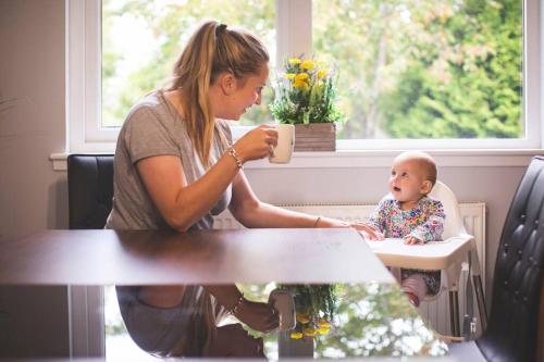 a woman sitting at a table with a baby in a high chair at Calm Scottish Country Escape with Hot Tub Sleeps 6 in Inverness