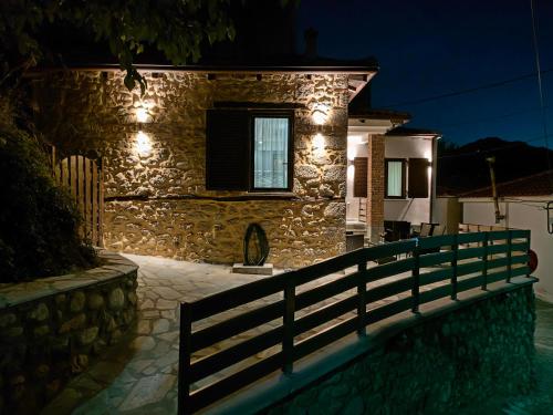 una casa de piedra con una valla delante de ella por la noche en Dream Nest Meteora, en Kalambaka