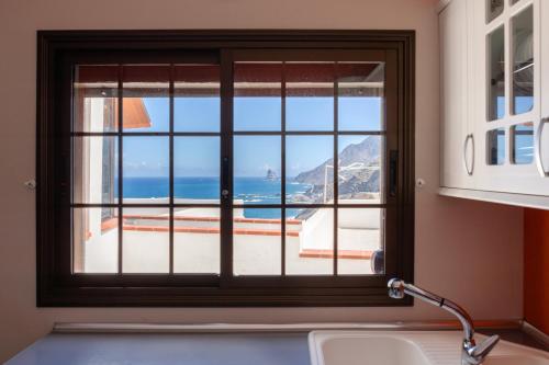 a kitchen window with a view of the ocean at Pearl of Nature: Serenity by the Sea in Azano
