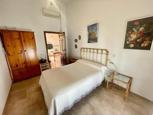 a bedroom with a white bed and a wooden cabinet at Casa De Los Baños in Cazalla de la Sierra