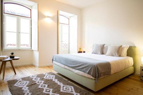 um quarto branco com uma cama e 2 janelas em Casa da Carta @ Casas do Pátio (3) em Coimbra