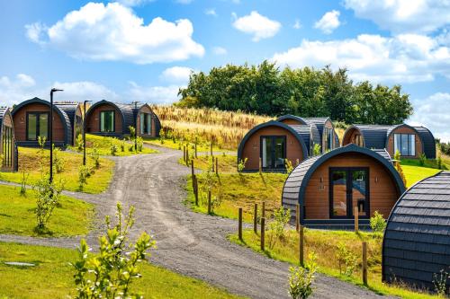 a row of cottages in a field with a dirt road at The Vu Snugs in Bathgate