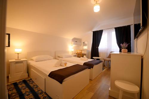 ein Hotelzimmer mit 2 Betten und einem Schreibtisch in der Unterkunft Pensiunea HERA Hațeg in Haţeg
