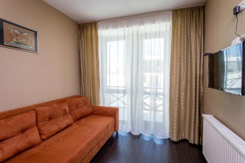 a living room with a couch and a large window at Bakuriani Residence in Bakuriani