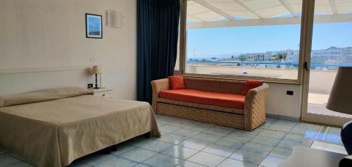 a bedroom with a bed and a chair and a window at Hotel Selenia Residence in Castro di Lecce