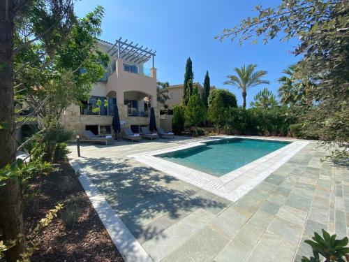 a villa with a swimming pool in front of a house at Phaedrus Living Amorosa 13 Beachside Villa in Polis Chrysochous