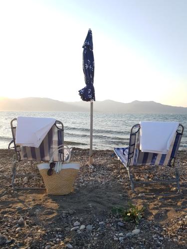 two chairs and an umbrella on the beach at Beach house in Skala Polichnitou, Lesvos, Greece in Lisvórion