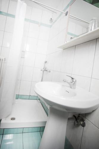 a white bathroom with a sink and a shower at Zappion Hotel in Athens