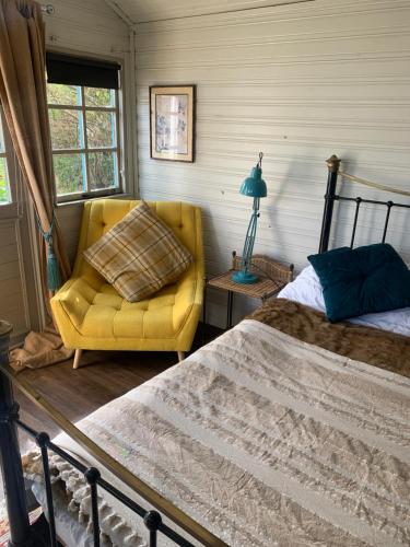 a bedroom with a bed and a yellow chair at The Cabin in Spixworth