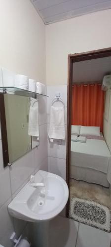 a bathroom with a white sink and a bed at Vila dos Bangalôs in Barreirinhas