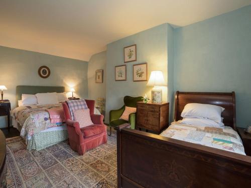 a bedroom with a bed and a chair in it at The Old Priory Cottage in Dunster